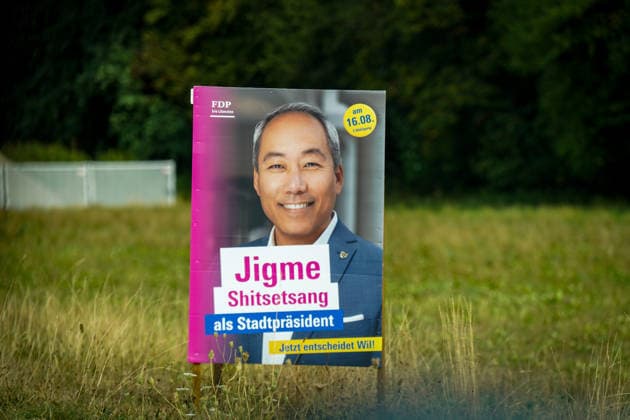 Schweiz: Politik, Wahlkampf in Wil (SG); Wahlplakat der FDP.Die Liberalen mit Jigme Shitsetsang, Kandidat für das Stadtpräsidium von Wil, vor dem zweiten Wahlgang am 16. August 2026. Das Plakat mit der Aufschrift Jigme Shitsetsang als Stadtpräsident Jetzt entscheidet Wil! steht auf einer Grünfläche. Symbolbild für Kommunalpolitik, Wahlen, FDP und Stadt Wil. *** Swiss Politics, Election Campaign in Wil, Canton of St. Gallen: Election poster for the FDP The Liberals featuring Jigme Shitsetsang, candidate for mayor of Wil, ahead of the second round of voting on August 16, 2026. The poster, bearing the slogan Jigme Shitsetsang for Mayor—Now It’s Up to Wil, is displayed on a green space. Symbolic image representing local po Copyright: xJOERANxSTEINSIEKx