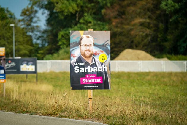 Schweiz: Politik, Wahlkampf in Wil (SG); Wahlplakat mit Michael Sarbach, Kandidat für den Stadtrat von Wil, vor dem zweiten Wahlgang am 16. August 2026. Das Plakat mit der Aufschrift Michael Sarbach in den Stadtrat steht am Strassenrand auf einer Grünfläche. Symbolbild für Kommunalpolitik, Stadtratswahl, Wahlen, Wahlkampf und Stadt Wil. *** Swiss Politics, Election Campaign in Wil, SG: Election poster featuring Michael Sarbach, candidate for the Wil City Council, ahead of the second round of voting on August 16, 2026. The poster, bearing the slogan Michael Sarbach for City Council, stands on the side of the road in a green space. Symbolic image representing local politics, city council elections, elections, election campaign Copyright: xJOERANxSTEINSIEKx