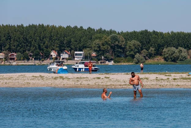 (260816) -- BELGRADE, Aug. 16, 2026 -- People cool off in the Danube River in Belgrade, Serbia, on Aug. 16, 2026. Riverbed was exposed as the water level of the Danube River approached record-low by severe drought. (Photo by Xinhua) SERBIA-BELGRADE-DANUBE RIVER-DROUGHT WangxWei 