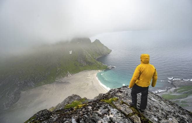 Wanderer am Gipfel des Helvetestinden, Ausblick auf Sandstrand Bunesstranden und blaues Meer, dramatischer Wolkenhimmel, Lofoten, Norwegen Hiker on Helvetestinden summit, view of Bunesstranden sandy beach and blue sea, dramatic cloudy sky, Lofoten, Norway Copyright: imageBROKER MaraxBrandl ibxmab18326816.jpg ,model released, Symbolfoto ,property released