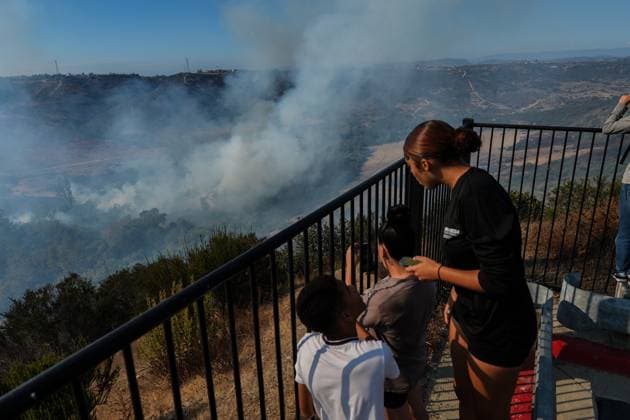 August 16, 2026, San Diego, California, United States: People watch the fire from the cliff edge..The Sorrento Fire burns through dry vegetation in the Sorrento Valley area of San Diego on August 16, 2026, sending thick smoke into the air and threatening nearby homes, businesses and roadways. Firefighters work to battle the flames and prevent the fire from spreading as smoke cover portions of the surrounding community. Multiple agencies are dispatched to battle the fire, including Cal Fire and San Diego Fire-Rescue. As of 6pm on August 16, the fire is mapped more than 100 acres. San Diego United States - ZUMAs197 20260816_aaa_s197_244 Copyright: xWaixLeexMichaelxHox