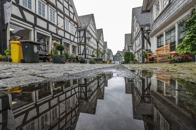 Wetterumschwung. Ein in den letzten Wochen eher seltenes Bild im Siegerland. Nach den trockenen heissen Tagen und Wochen startet die neue Woche nass und verhaeltnismaessig (verhältnismäßig) kuehl (kühl). Die Historische Altstadt von Freudenberg mit ihren Fachwerkhaeusern (Fachwerkhäusern). Die Haeuser (Häuser) spiegeln sich ein einer Pfuetze (Pfütze). Sommer im Siegerland am 17.08.2026 in Freudenberg Deutschland. *** Weather Change: A rare sight in the Siegerland region in recent weeks. After days and weeks of dry, hot weather, the new week is starting off wet and relatively cool. The historic old town of Freudenberg with its half-timbered houses. The haehouses are reflected in a puddle. Summer in the Siegerland region on August 17,