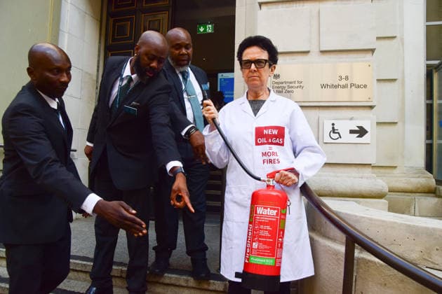 August 17, 2026, London, England, United Kingdom: Security personnel try to move a climate activist from the group Scientists On Survival standing outside the Department for Energy Security and Net Zero (DESNZ) in Westminster with a fire extinguisher after spraying the building with water in protest against Rosebank, as the public consulation on the North Sea oil and gas field concludes. London United Kingdom - ZUMAv130 20260817_zip_v130_016 Copyright: xVukxValcicx