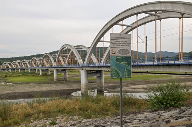 Historic summer heatwave drains southern Poland waterways ZEMBRZYCE, POLAND - AUGUST 17: An information sign detailing the Swinna Poreba Reservoir fishing district stands next to a dried-up river basin beneath a large arched railway bridge in Zembrzyce, southern Poland, on August 17, 2026. A record-breaking summer heatwave and acute lack of precipitation have caused water levels to plummet by over a meter, drastically shrinking the vital waterway to a shallow stream. The severe hydrological drought has forced regional authorities to enforce emergency water restrictions across the Malopolska province. Artur Widak Anadolu Zembrzyce Poland. Editorial use only. Please get in touch for any other usage.  Copyright: x2026xAnadoluxArturxWidakx