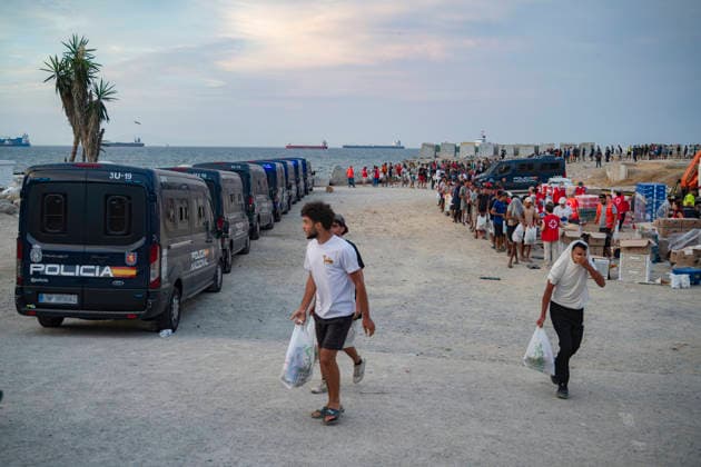 The humanitarian crisis in Ceuta continues. Several migrants wait in line for food on a beach on August 19, 2026, in Ceuta, Spain. Ceuta continues to face a serious humanitarian crisis following the historic mass influx of more than 70,000 migrants who swam across the Tarajal Strait on July 30 and 31. Although the police deployment and border reinforcement by by Moroccan authorities have succeeded in curbing the influx, the autonomous city continues to face a serious humanitarian crisis, health, and security crises. AUGUST 19, 2026 CEUTA MIGRATION CRISIS MIGRANTS IMMIGRANTS SPRINGBOARD TARAJAL BENÍTEZ BEACH (BLURRED) Ceuta Ceuta, Spain  Copyright: xMarcosxMorenox 7721859