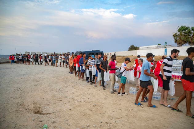 The humanitarian crisis in Ceuta continues. Several migrants wait in line for food on a beach on August 19, 2026, in Ceuta, Spain. Ceuta continues to face a serious humanitarian crisis following the historic mass influx of more than 70,000 migrants who swam across the Tarajal on July 30 and 31. Although the current police deployment and border reinforcement by by Moroccan authorities have managed to stem the influx, the autonomous city continues to face a serious humanitarian crisis, health, and security crises. AUGUST 19, 2026 CEUTA MIGRATION CRISIS MIGRANTS IMMIGRANTS TRAMPOLÍN TARAJAL PLAYA BENÍTEZ Ceuta Ceuta, Spain  Copyright: xMarcosxMorenox 7721842