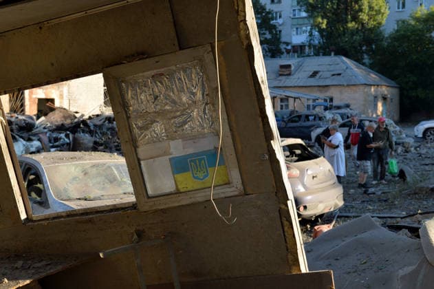 A poster with a Ukrainian flag and coat of arms (tryzub) is pictured in a security booth at a parking lot outside an apartment block in the Solomianskyi district after a Russian missile attack, Kyiv, Ukraine, August 20, 2026. High-rise residential buildings, a children’s hospital, a school, utility and warehouse facilities, garages, and cars were damaged in the district as a result of Russia’s overnight large-scale combined strike on the capital. Power grid infrastructure was also affected, causing an outage. In Kyiv, the attack claimed the lives of at least 13 people, including two children. The Russian military targeted the city with ballistic missiles, Kalibr cruise missiles, Kh-101s, and Zircon hypersonic cruise missiles. (Photo by Olek  Copyright: xOleksandrxKlymenkox