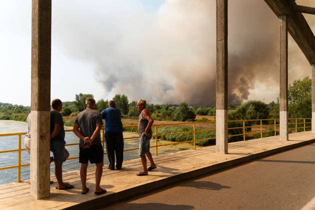 August 20, 2026, Grebenac, Vojvodina, Serbia: 2026820, Grebenac, Serbia - A massive wildfire that has been burning for weeks in the Deliblatska pescara, Special Nature Reserve has reached the village of Grebenac, as locals, firefighters, and military helicopters battle to bring the blaze under control. A group of concerned villagers gathers on a local bridge to observe the massive smoke cloud. Grebenac Serbia - ZUMAd223 20260820_zip_d223_011 Copyright: xMarkoxDimicx