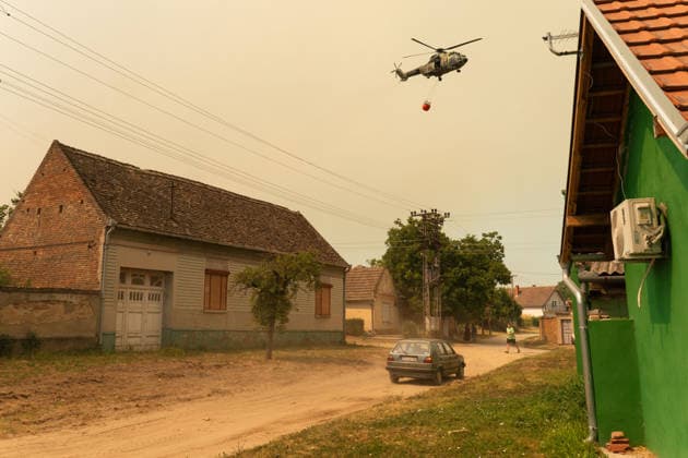August 20, 2026, Grebenac, Vojvodina, Serbia: 2026820, Grebenac, Serbia - A massive wildfire that has been burning for weeks in the Deliblatska pescara, Special Nature Reserve has reached the village of Grebenac, as locals, firefighters, and military helicopters battle to bring the blaze under control. A firefighting helicopter carrying a water bucket flies low over the streets of Grebenac. Grebenac Serbia  - ZUMAd223 20260820_zip_d223_015 Copyright: xMarkoxDimicx