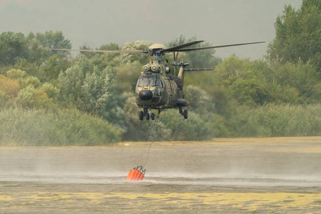 August 20, 2026, Grebenac, Vojvodina, Serbia: 2026820, Grebenac, Serbia - A massive wildfire that has been burning for weeks in the Deliblatska pescara, Special Nature Reserve has reached the village of Grebenac, as locals, firefighters, and military helicopters battle to bring the blaze under control. A military helicopter hovers over a nearby river to fill its Bambi bucket with water for aerial firefighting operations. Grebenac Serbia  - ZUMAd223 20260820_zip_d223_019 Copyright: xMarkoxDimicx