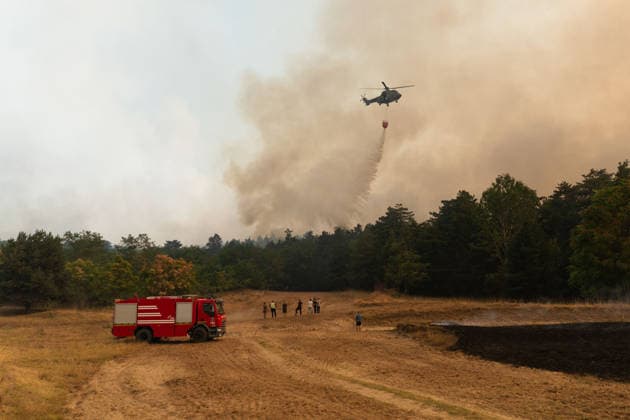 August 20, 2026, Grebenac, Vojvodina, Serbia: 2026820, Grebenac, Serbia - A massive wildfire that has been burning for weeks in the Deliblatska pescara, Special Nature Reserve has reached the village of Grebenac, as locals, firefighters, and military helicopters battle to bring the blaze under control. Firefighters and local volunteers stand near a fire engine as a Super Puma helicopter performs an aerial water drop over the burning forest. Grebenac Serbia  - ZUMAd223 20260820_zip_d223_025 Copyright: xMarkoxDimicx