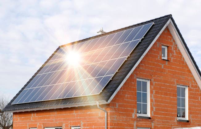 Eine PV-Solar- Anlage auf einem Hausdach Eine Photovoltaikanlage auf dem Hausdach von einem Neubau erzeugt grünen Strom - FOTOMONTAGE - NUR FÜR REDAKTIONELLE VERWENDUNG -