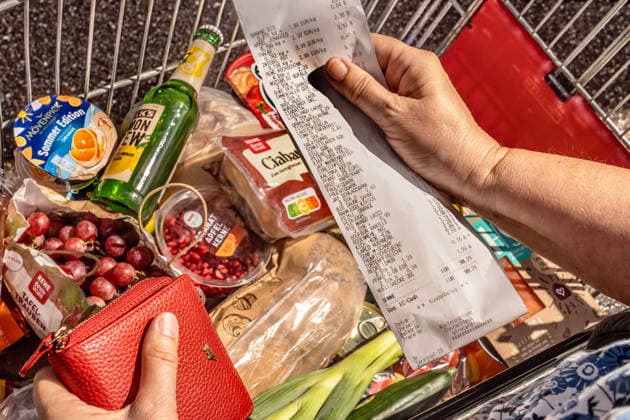 Lebensmittel einkaufen im Supermarkt, voller Einkaufswagen, Kundin kontrolliert den Kassenbon, München, August 2026 Deutschland, München, August 2026, Lebensmittel einkaufen im Supermarkt, voller Einkaufswagen, Kundin kontrolliert den Kassenbon, der komplette Einkauf kostet fast 100 Euro (nicht alle gekauften Waren im Foto zu sehen), Symbolfoto Lebensmittelpreise, Inflation, Wirtschaft,