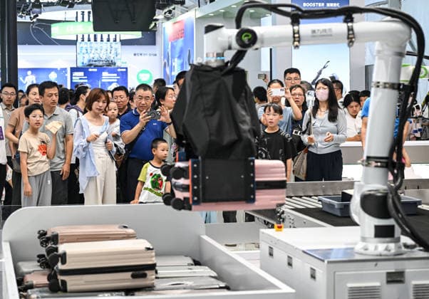 (260822) -- BEIJING, Aug. 22, 2026 -- People view a robotic arm carrying a suitcase through a security screening machine at the 2026 World Robot Conference in Beijing, capital of China, Aug. 22, 2026. The conference, which runs from Wednesday through Sunday, has drawn more than 300 exhibitors from 26 countries, with over 3,000 products on display, including more than 300 debuts. Many people visited the conference on Saturday, the first open day of the event. ) CHINA-BEIJING-WORLD ROBOT CONFERENCE (CN) ChenxYehua 