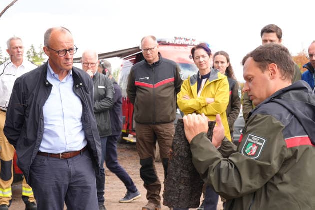Bundeskanzler Merz besucht Waldbrandgebiet Huertgenwald Der Foerster Jan-Valentin Wiesmeyer erlaeutert Bundeskanzler Friedrich Merz anhand einer Baumrinde die Folgen des Bandes bei der Besichtigung des ehemaligen Waldbrandgebiet in Huertgenwald, , 22.08.2026 Huertgenwald (Kreis Dueren) Nordrhein-Westfalen Deutschland *** Chancellor Merz Visits the Huertgenwald Forest Fire Area. During a tour of the former forest fire area in Huertgenwald, forester Jan Valentin Wiesmeyer explains the effects of the fire to Chancellor Friedrich Merz using a piece of tree bark as an example, , August 22, 2026, Huertgenwald, Düren District, North Rhine-Westphalia, Germany