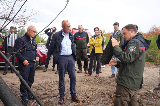 Bundeskanzler Merz besucht Waldbrandgebiet Huertgenwald Der Foerster Jan-Valentin Wiesmeyer erlaeutert Bundeskanzler Friedrich Merz anhand einer Baumrinde die Folgen des Bandes bei der Besichtigung des ehemaligen Waldbrandgebiet in Huertgenwald, , 22.08.2026 Huertgenwald (Kreis Dueren) Nordrhein-Westfalen Deutschland *** Chancellor Merz Visits the Huertgenwald Forest Fire Area. Forester Jan Valentin Wiesmeyer explains the effects of the fire to Chancellor Friedrich Merz using a piece of tree bark as an example during a tour of the former forest fire area in Huertgenwald, , August 22, 2026, Huertgenwald, Düren District, North Rhine-Westphalia, Germany