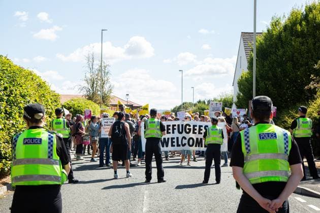 August 22, 2026, Gloucester, GB: GLOUCESTER, ENGLAND, AUGUST 22, 2026: An activist holds a sign reading Ã¢â‚¬oeRefugees WelcomeÃ¢â‚¬Â while walking through a residential street during a protest in Gloucester. The demonstration was held amid debate over the accommodation of migrants in local hotels. Gloucester GB  - ZUMAq101 20260822_zna_q101_121 Copyright: xEthanxFowlerx