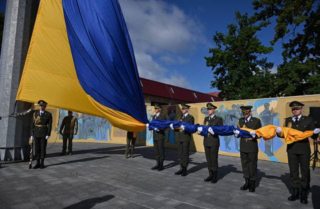National Flag Day of Ukraine in Lviv LVIV, UKRAINE - AUGUST 23: Ukrainian servicemen hold a large national flag during a National Flag Day ceremony in Lviv, Ukraine, on August 23, 2026. Due to the ongoing Russian-Ukrainian War, celebrations were limited to a ceremonial raising of the Ukrainian flag on the city s highest flagpole with the participation of soldiers from various branches of the armed forces. Participants also observed a minute of silence for those killed, sang the Ukrainian national anthem, and listened to patriotic and folk songs performed by a military orchestra. Michael Sorrow Anadolu Lviv Ukraine. Editorial use only. Please get in touch for any other usage.  Copyright: x2026xAnadoluxMichaelxSorrowx