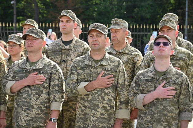 National Flag Day of Ukraine in Lviv LVIV, UKRAINE - AUGUST 23: Ukrainian servicemen place their hands over their hearts during a National Flag Day ceremony in Lviv, Ukraine, on August 23, 2026. Due to the ongoing Russian-Ukrainian War, celebrations were limited to a ceremonial raising of the Ukrainian flag on the city s highest flagpole with the participation of soldiers from various branches of the armed forces. Participants also observed a minute of silence for those killed, sang the Ukrainian national anthem, and listened to patriotic and folk songs performed by a military orchestra. Michael Sorrow Anadolu Lviv Ukraine. Editorial use only. Please get in touch for any other usage.  Copyright: x2026xAnadoluxMichaelxSorrowx