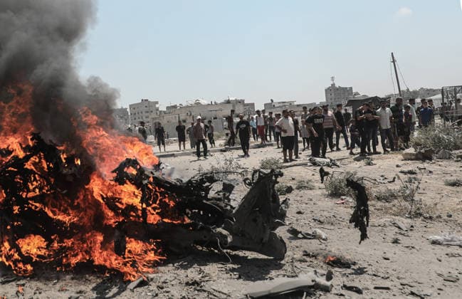 Palestinians look at a burning lorry between the areas of Maghazi and al-Zawayda following an Israeli strike, carried out after the military warned Palestinian residents to evacuate the area of al-Zawayda, in the central Gaza Strip, on Sunday on August 23, 2026. Israeli strikes in the central Gaza Strip killed three people including a child, rescuers said.  GAZ2026082302 AbedxSalhi