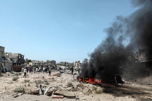 Palestinians look at a burning lorry between the areas of Maghazi and al-Zawayda following an Israeli strike, carried out after the military warned Palestinian residents to evacuate the area of al-Zawayda, in the central Gaza Strip, on Sunday on August 23, 2026. Israeli strikes in the central Gaza Strip killed three people including a child, rescuers said.  GAZ2026082313 AbedxSalhi