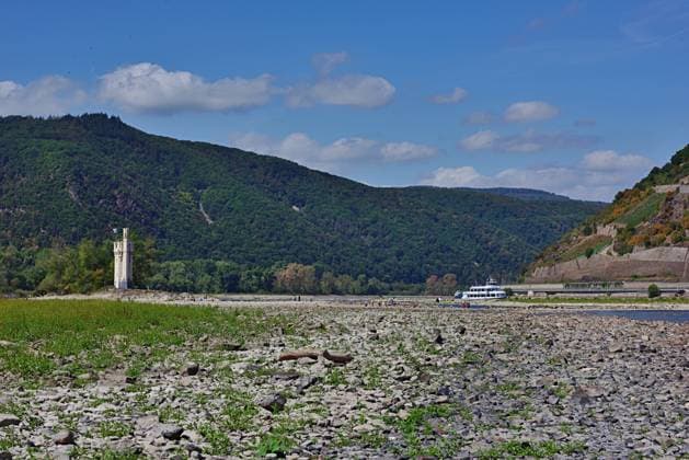 23.8.2026 Dürre Der extrem niederige Wasserstand des Rhein. Große Teile des Binger Lochs an de Nahemündung liegen trocken. Die Menschen spazieren dort wo sonst meterhoch das Wasser fließt. Die Fahrrinne für die Schifffahrt ist nur eingeschränkt nutzbar. Bingen Rhein Rheinland Pfalz Deutschland *** August 23, 2026 Drought The water level of the Rhine is extremely low. Large parts of the Binger Loch at the mouth of the Nahe are dry. People are walking where the water would normally flow meters high. The shipping channel is only partially usable. Bingen, Rhine, Rhineland-Palatinate, Germany