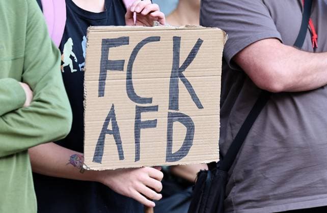 Wahlkampf der AfD zur Landtagswahl in Sachsen-Anhalt 24.08.2026, Naumburg, Wahlkampf der AfD auf dem Naumburger Marktplatz, am 06.09.2026 wird der neue Landtag in Sachsen-Anhalt gewaehlt im Bild: Gegenveranstaltung auf dem Holzmarkt - ein Plakat mit der Aufschrift FCK AfD, der Traeger des Schildes hat ein Klebetattoo eines Einhorns am Arm *** AfD campaign for the state election in Saxony-Anhalt, August 24, 2026, Naumburg, AfD campaign rally on Naumburg’s market square; on September 6, 2026, the new state parliament of Saxony-Anhalt will be elected. Pictured: a counter-rally on the Holzmarkt featuring a poster reading FCK AfD ; the person holding the sign has a unicorn sticker on their arm