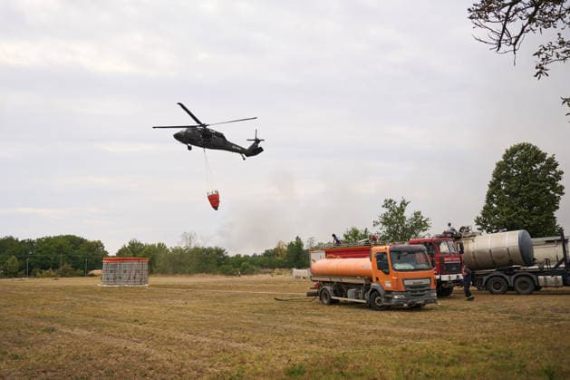 August 25, 2026, Susara, Vojvodina, Serbia: 2026825, Susara, Serbia - Two Sikorsky UH-60 Black Hawk helicopters are deployed to the village of Susara to help battle the severe wildfires devastating the Deliblato Sands (Deliblatska Pescara) Special Nature Reserve, refilling their buckets from a large portable water tank placed on a local football pitch. Susara Serbia - ZUMAd223 20260825_zip_d223_001 Copyright: xMarkoxDimicx