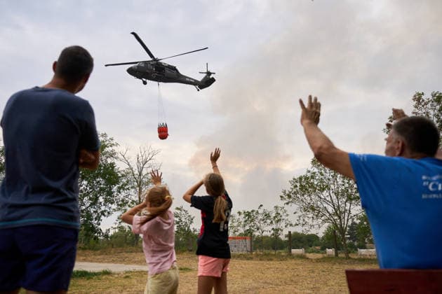 August 25, 2026, Susara, Vojvodina, Serbia: 2026825, Susara, Serbia - Two Sikorsky UH-60 Black Hawk helicopters are deployed to the village of Susara to help battle the severe wildfires devastating the Deliblato Sands (Deliblatska Pescara) Special Nature Reserve, refilling their buckets from a large portable water tank placed on a local football pitch. Local residents wave to the helicopter crew. Susara Serbia  - ZUMAd223 20260825_zip_d223_009 Copyright: xMarkoxDimicx