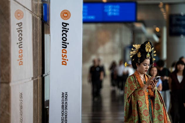 Bitcoin Asia Hong Kong 2026 A woman dress in a Chinese Hanfu looks at her phone next to a Bitcoin Asia logo at Bitcoin Asia 2026 on August 27, 2026 in Hong Kong. (Photo by Vernon Yuen Nexpher Images) HONG KONG