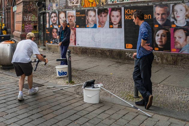 Der Schauspieler Ulrich Matthes beim Anbringen von Fotos mit Schauspielern des Deutschen Theaters zur Eröffnung der Spielzeit 2026 2027 an eine Plakatwand unter dem S-Bahnhof Hackescher Markt in Berlin-Mitte. *** Actor Ulrich Matthes putting up photos featuring actors from the Deutsches Theater on a billboard beneath the Hackescher Markt S-Bahn station in Berlin-Mitte to mark the opening of the 2026–2027 season