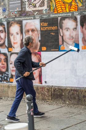 Der Schauspieler Ulrich Matthes beim Anbringen von Fotos mit Schauspielern des Deutschen Theaters zur Eröffnung der Spielzeit 2026 2027 an eine Plakatwand unter dem S-Bahnhof Hackescher Markt in Berlin-Mitte.