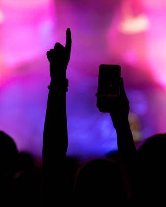 Eine Festivalbesucherin hält beim Auftritt von Ski Aggu auf dem Glücksgefühle Festival auf dem Hockenheimring eine Hand mit dem Handy und eine andere Hand mit ausgestrecktem Finger hoch. Hockenheim Baden-Württemberg Deutschland