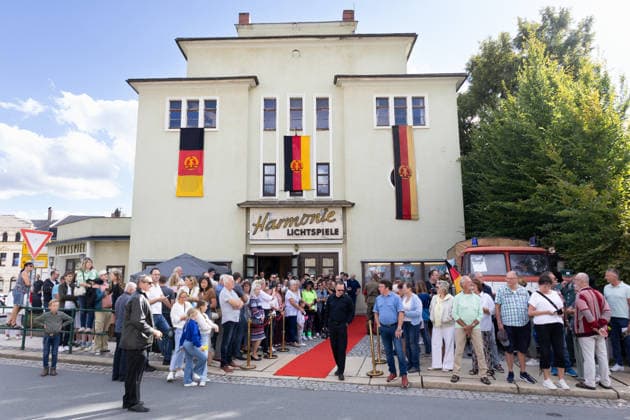 05.09.2026, Filmpremiere, Maske auf Genossen Blick auf den Eingangsbereichs des Kinos mit DDR-Fahnen an den Fenstern Markneukirchen Harmonie-Lichtspiele Sachsen Deutschland