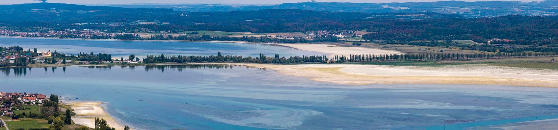 Ausblick auf die Insel Reichenau im Bodensee. Rechts der Reichenauer Damm mit Platanenallee, ein Teil der Deutschen Allenstraße. Das Seeufer zeigt den niedrigen Wasserstand nach einem heißen Sommer. 27.08.2026, Ermatingen, Kanton Thurgau, Schweiz