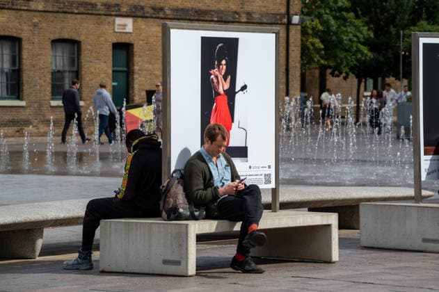 September 9, 2026, London, United Kingdom: Two visitors seen sitting near a portrait of Amy Winehouse displayed as part of the ˜Amy Winehouse. Visitors view ˜Amy Winehouse: In Focus™, a free outdoor photography exhibition at Granary Square and King™s Boulevard in King™s Cross, London. The exhibition features defining and previously unseen photographs of the late singer, offering an intimate portrait of her life and career and marking 20 years since the release of her acclaimed album ˜Back to Black™. The exhibition runs from 1 September to 15 October 2026. London United Kingdom - ZUMAs197 20260909_aaa_s197_580 Copyright: xJamesxWilloughbyx