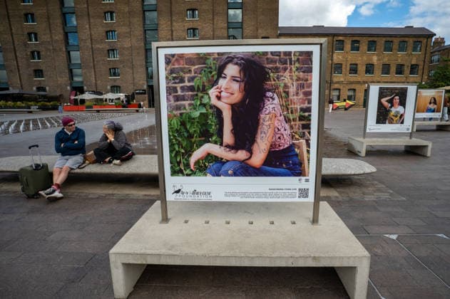 September 9, 2026, London, United Kingdom: Two visitors seen sitting beside a portrait of the late singer in Granary Square, King™s Cross. Visitors view ˜Amy Winehouse: In Focus™, a free outdoor photography exhibition at Granary Square and King™s Boulevard in King™s Cross, London. The exhibition features defining and previously unseen photographs of the late singer, offering an intimate portrait of her life and career and marking 20 years since the release of her acclaimed album ˜Back to Black™. The exhibition runs from 1 September to 15 October 2026. London United Kingdom - ZUMAs197 20260909_aaa_s197_592 Copyright: xJamesxWilloughbyx