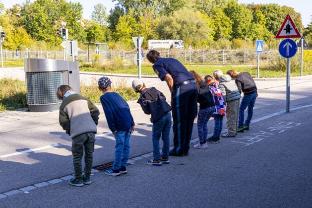 Schulwegtraining mit der Verkehrspolizeiinspektion Augsburg vor dem Schulanfang in Bayern. Kinder üben beim Schulwegtraining in Augsburg mit einer Polizistin das sichere Überqueren einer Straße. Vor dem Queren schauen sie aufmerksam nach links und rechts und trainieren richtiges Verkehrsverhalten