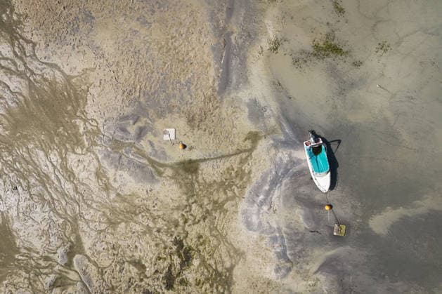 Wetterfeature, Bei sonnigem Spätsommerwetter am Bodensee liegen einige Boote aufgrund des niedrigen Wasserstands auf dem Trockenen. Gleichzeitig zeigt sich der Bodensee von seiner malerischen Seite das Wasser schimmert bei strahlendem Sonnenschein grünlich-blau, während sich die Uferlandschaft unter nahezu wolkenlosem Himmel präsentiert. (Aufnahme mit einer Drohne) Moos Baden-Württemberg Deutschland Moos
