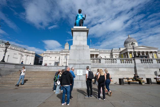 September 12, 2026, London, United Kingdom: People read the plaque at the base of the Fourth Plinth, currently showcasing the sculpture Lady in Blue, in Trafalgar Square, London. Lady in Blue, a bronze sculpture by New York-based artist Tschabalala Self, stands on the Fourth Plinth in Trafalgar Square, London. Unveiled on 10 September, the work pays homage to a young metropolitan woman of colour and was created as a contemporary everywoman representing the diversity of London today. The sculpture explores themes of representation, recognition and equity, presenting an everyday woman walking forward into a shared future rather than a traditional historical figure or monument. The bronze sculpture is patinated in Lapis Lazuli blue, a pi - ZUMAs197 20260912_aaa_s197_272 Copyright: xAndreaxDomeniconix
