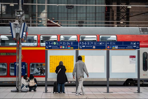 Eine reisende Frau steht auf Gleis 6 7 und schaut sich den Fahrplan an, während sie von einem Bettler angesprochen wird, im Hintergrund steht der Nahverkehrszug RB81 nach Bad Oldesloe;Deutsche Bahn AG Hamburg Hbf, Hamburg Hamburg Deutschland Hauptbahnhof
