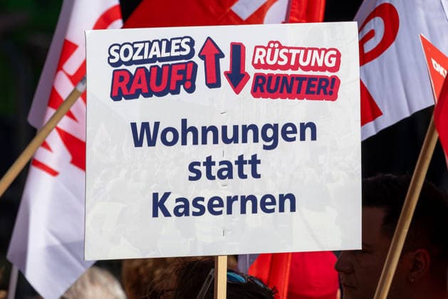 DGB Bayern - Hart verdient! Groß-Kundgebung, Nürnberg, 26.09.2026 Ein Demonstrationsschild mit der Forderung Soziales rauf! Rüstung runter! Wohnungen statt Kasernen wird bei einer Kundgebung hochgehalten. Im Hintergrund sind rote Fahnen von Gewerkschaften und Teilnehmenden zu erkennen. Nürnberg Bayern Deutschland