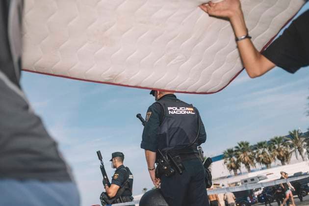 September 26, 2026, Ceuta, Ceuta, Spain: Spanish National Police officers stand guard on the seafront of Ceuta, seen past a mattress carried by a migrant. Thousands of migrants, most of them young Moroccan men, have been living in makeshift settlements in the Spanish North African enclave of Ceuta since a mass arrival at the end of July 2026 set off a migration and political crisis. Ceuta Spain - ZUMAs392 20260926_zip_s392_003 Copyright: xFabianxSuspensivox