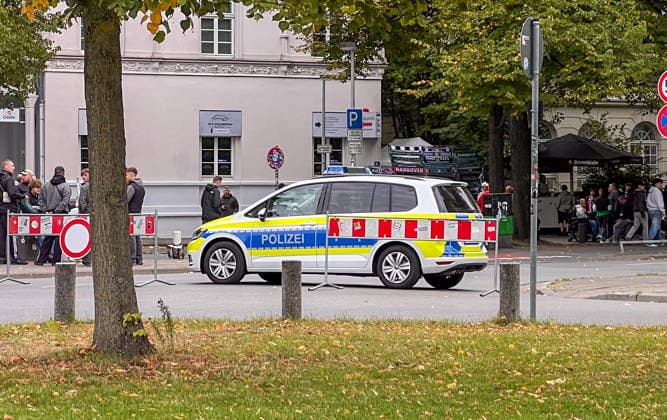 Hannover, Niedersachsen, Deutschland, Europa. Ein Einsatzfahrzeug der Polizei steht vor einer Gruppe von Fußballfans im Umfeld einer Veranstaltung. Absperrgitter, Zuschauer und Fanartikel sind im Hintergrund zu sehen. Symbolbild für Polizeieinsatz, Sicherheitsmaßnahmen, Fußball, Fans, öffentliche Ordnung und Großveranstaltungen. Copyright: xAymanxAlahmedx