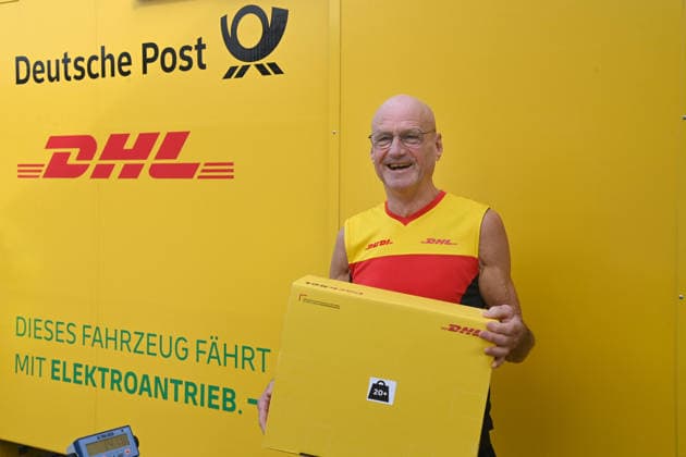 Paketzusteller Rudi VAN DEN BOSSCHE haelt ein Paket in der Hand, an seinem Zustellfahrzeug, Minister Laumann besucht Zustellbasis von Deutscher Post und DHL, Duesseldorf am 28.09.2026,