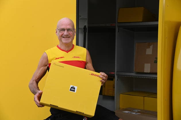 Paketzusteller Rudi VAN DEN BOSSCHE haelt ein Paket in der Hand, an seinem Zustellfahrzeug, Minister Laumann besucht Zustellbasis von Deutscher Post und DHL, Duesseldorf am 28.09.2026,
