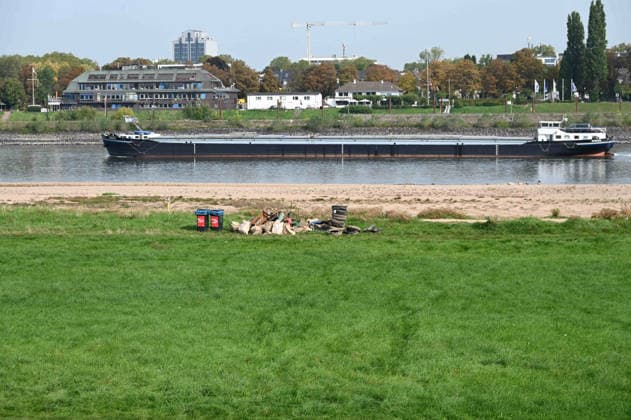 Das Niedrigwasser im Rhein hat eine grosse Sandbank freigelegt, Steine und Sand am Ufer, nahe der Theodor Heuss Bruecke, ein Frachtschiff faehrt in der Fahrrinne, im Vordergrund Treibgut, Autoreifen und Unrat wurden vom Niedrigwasser freigegeben, Unbekannte haben den Muell gesammelt und am Ufer zur Abholung abgelegt, Niedrigwasser im Rhein bei Duesseldorf, Duesseldorf am 28.09.2026,