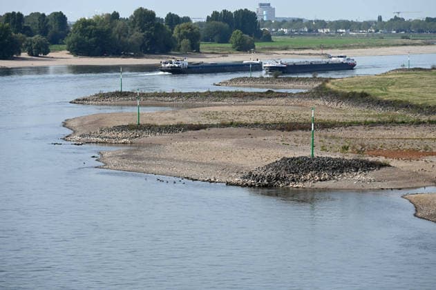 Das Niedrigwasser im Rhein hat eine grosse Sandbank freigelegt, Steine und Sand am Ufer, gesehen von der Rheinkniebruecke, ein Frachtschiff faehrt in der Fahrrinne, Niedrigwasser im Rhein bei Duesseldorf, Duesseldorf am 28.09.2026,