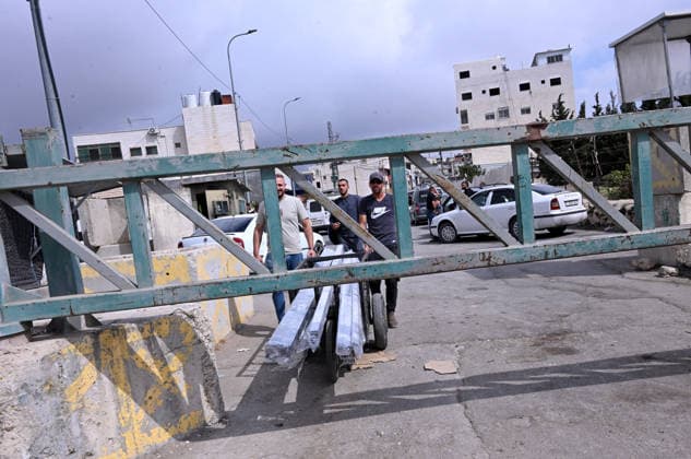 Palestinians push a cart carrying construction materials under an Israeli erected locked gate that blocks cars from moving to and from the village of Sair, near Hebron in the West Bank, on Tuesday, September 29, 2026. Israel declared a West Bank military closure to restrict Palestinian movement during the Jewish holiday of Sukkot from September 27 - October 3, 2026.  JER2026092915 DEBBIExHILL