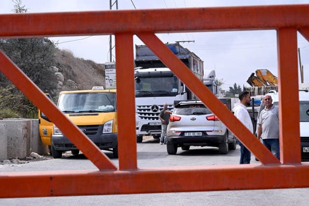 Palestinians stand behind an Israeli erected locked gate that blocks cars from moving to and from Halhul near Hebron in the West Bank, on Tuesday, September 29, 2026. Israel declared a West Bank military closure to restrict Palestinian movement during the Jewish holiday of Sukkot from September 27 - October 3, 2026.  JER2026092902 DEBBIExHILL